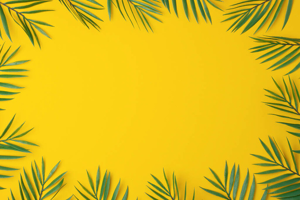 Yellow background with palm leaves. Flat lay, copy space - Φωτογραφία, εικόνα