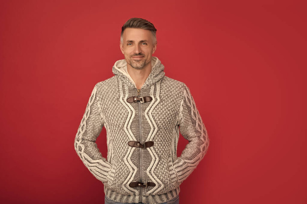 hair and skin care. grizzled guy in sweater on red background. hoary man portrait. male fashion model with hands in pocket. winter fashion. mens beauty. - Foto, Imagen