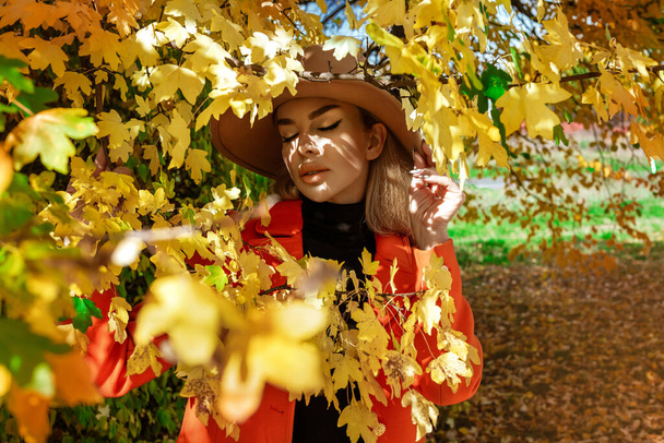 Mooie vrouw draagt herfstkleding in de herfst landschap met kleurrijke bladeren. Buiten schieten. Herfstmode. - Foto, afbeelding
