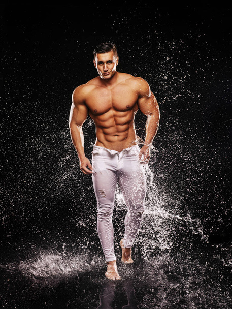 Grinning sexy bodybuilder in white jeans walking on water - Foto, afbeelding