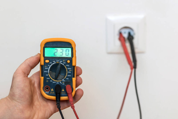 Measuring Voltage by Tester. Digital Multimeter in Hole of Electric Socket. Electrician Service. - Photo, Image