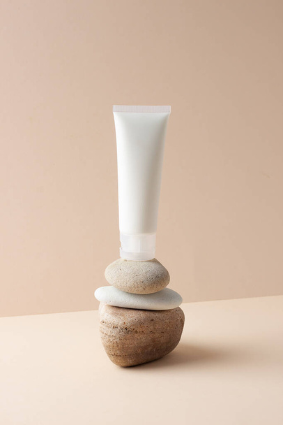 White tube of cosmetic cream on a stone podium on beige background. Close up. - Fotoğraf, Görsel
