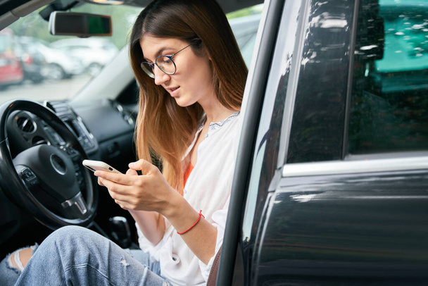 Güzel kadın sürücü cep telefonu kullanıyor. Mesaj okuyor. Arabada oturuyor, kopyalama alanı kullanıyor. Ulaşım, araba paylaşım kavramı  - Fotoğraf, Görsel