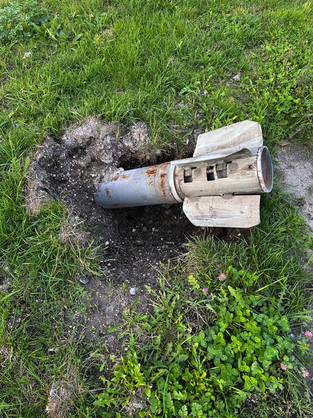 ロシアのMLRSウクライナの占領地域から解放された芝生の横に地面にグレードの発射物。ロシアの砲撃の結果。戦争、ロシアの侵略と軍事犯罪の概念. - 写真・画像