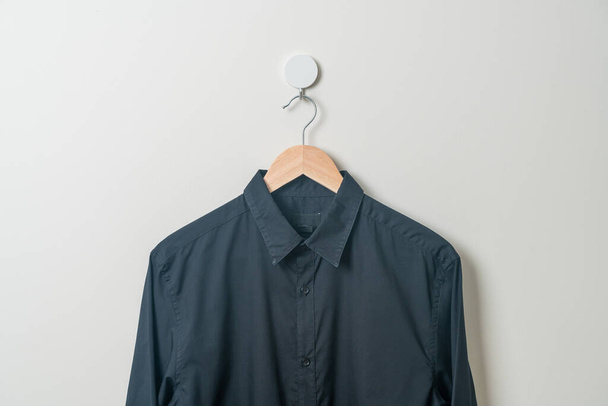 hanging black shirt with wood hanger on wall - 写真・画像