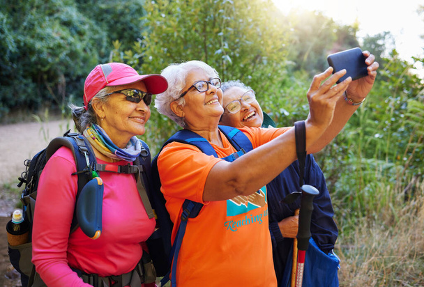 Senior women, phone selfie and hiking in nature on holiday or summer vacation. Travel, hike and retired friends spending time together on 5g mobile tech, happy memory or picture post for social media. - Zdjęcie, obraz