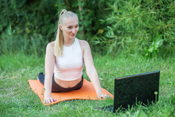 Woman practicing stretching lesson online outdoors. Playing sports, following guidance or instructions of trainer. Copy space. - Foto, imagen