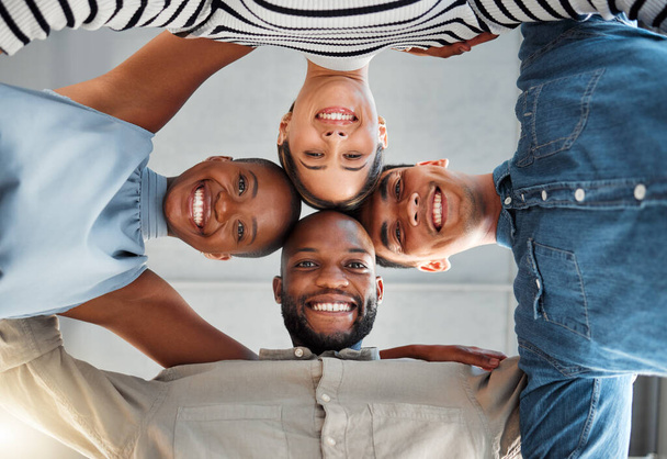 Portrait of a group of young diverse businesspeople smiling and huddling in support at work. Cheerful colleagues standing united to motivate each other. Faces of happy coworkers in an office. - Photo, Image