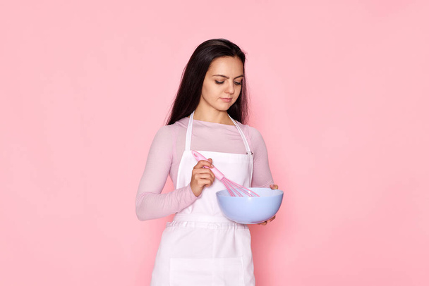 beautiful chef woman using bowl and whisk on pink background - Photo, Image