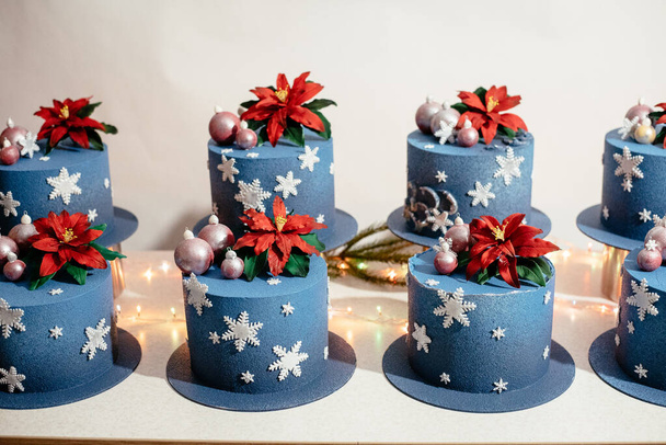 Vitrine met taarten gedecoreerd in nieuwjaarsstijl. Feestelijke kersttaart versierd met bollen en sneeuwvlokken. Kerstdessert - Foto, afbeelding