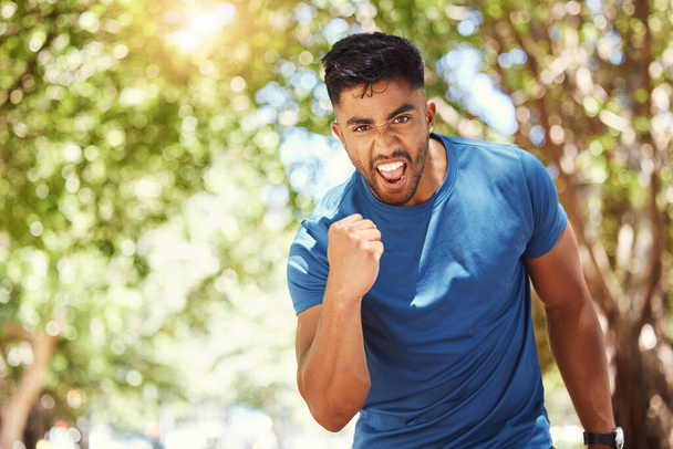 Portret młodego mieszanego sportowca wyglądającego na zmotywowanego i podekscytowanego wygraną. Hiszpan świętujący zwycięstwo i wyrażający radość podczas ćwiczeń i skupienia się na kondycji w parku - Zdjęcie, obraz