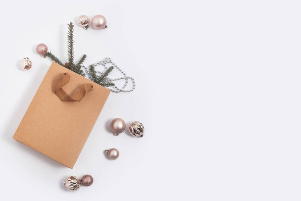 Ramas de abeto en una bolsa de regalo artesanal, bolas decorativas sobre un fondo blanco. Vista superior, plano - Foto, imagen