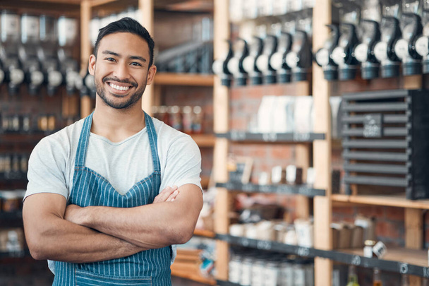 Portrait of one happy young hispanic waiter standing with his arms crossed in a store or cafe. Friendly man and coffeeshop owner managing a successful restaurant startup. - Photo, Image