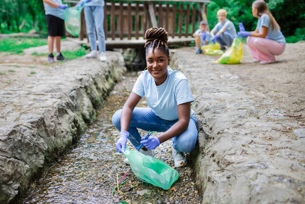 Γυναίκα μαζεύει σκουπίδια από πλαστικά καλαμάκια από το ποτάμι στο πάρκο. Παγκόσμια ημέρα περιβάλλοντος.. - Φωτογραφία, εικόνα