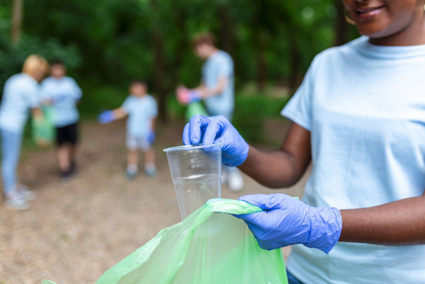 Een multi-etnische groep mensen, die samen schoonmaken in een openbaar park, beschermt het milieu. Het concept van recycling en reiniging - Foto, afbeelding