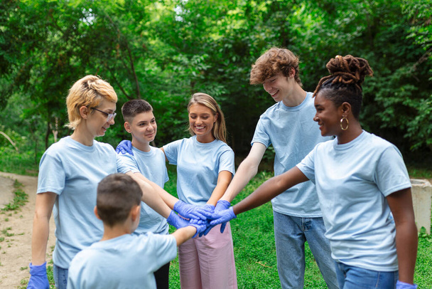 Retrato de voluntários dobrando os braços. Ambientalistas estão em um parque público. Eles estão em camisetas azuis. O conceito de amizade e ajuda - Foto, Imagem