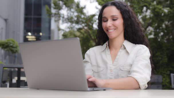 ノートパソコンでテキストを入力するビジネスマン女性ジャーナリスト屋外に座って、白人30代の女性の顧客女性オンラインショッピングコンピュータアプリのウェブサイトで予約する外のカフェで無料のWi-Fiを使用して - 映像、動画