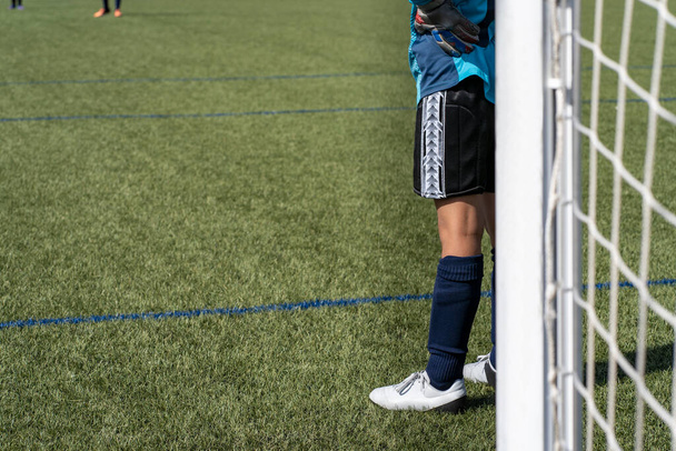 Acción de portero de fútbol irreconocible en el gol del campo de fútbol de césped artificial en una competición infantil. - Foto, imagen