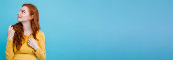 Portrait de fille rousse gingembre heureux avec des taches de rousseur souriant regardant la caméra. Fond bleu pastel. Espace de copie
. - Photo, image