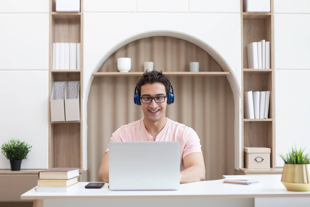 Молодий красивий чоловік в навушниках вивчає онлайн вдома. Концепція дистанційної освіти
 - Фото, зображення