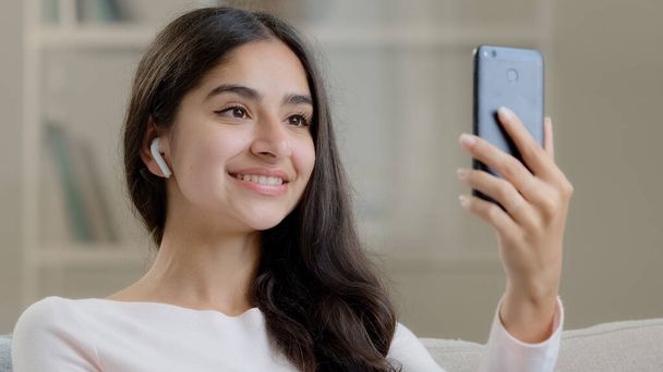 Piękny arabski Bliski Wschód dziewczyna nastolatek nosi słuchawki bezprzewodowe rozmowy w komórkowej kamery nagrywania bloga social media streaming robienie selfie w domu wideo dzwoniąc w czacie online z chłopakiem - Zdjęcie, obraz