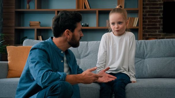 Caring father caucasian man dad trying to contact with offended child girl helping little kid daughter talking sincerely about misunderstanding problem mistrust between children and parents in family - Foto, Imagem