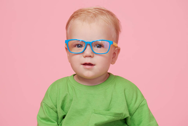 Portrait of male baby boy on pink background wearing glasses and looking at the camera. Smart baby concept - Valokuva, kuva