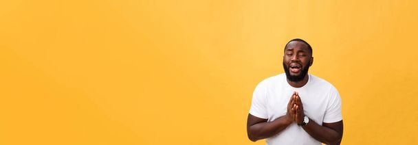 Portrait studio du jeune Afro-Américain en chemise blanche, tenant la main dans la prière, regardant la caméra avec une expression sceptique réfléchie sur son visage, soupçonnant quelque chose. Langage corporel
 - Photo, image