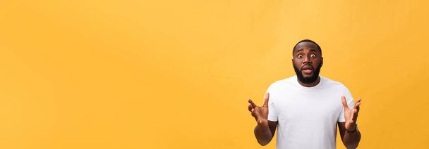 Portrait of african american man with hands raised in shock and disbelief. Isolated over yellow background - Φωτογραφία, εικόνα