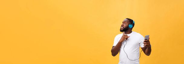 African American man z słuchawki słuchać i tańczyć przy muzyce. Na białym tle na żółtym tle. - Zdjęcie, obraz