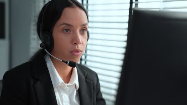 Competent african american female operator working on computer and while talking with clients. Concept relevant to both call centers and customer service offices. - Filmmaterial, Video