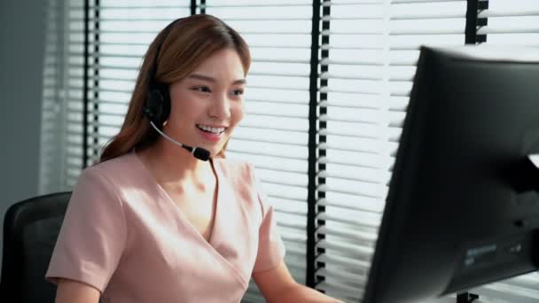 Competent female operator working on computer and while talking with clients. Concept relevant to both call centers and customer service offices. - Záběry, video
