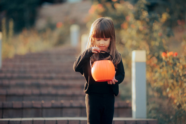 Little Halloween Girl Checking her Pumpkin Candy Bucket - Photo, image