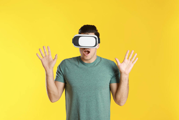 Man using virtual reality headset on yellow background - Foto, afbeelding