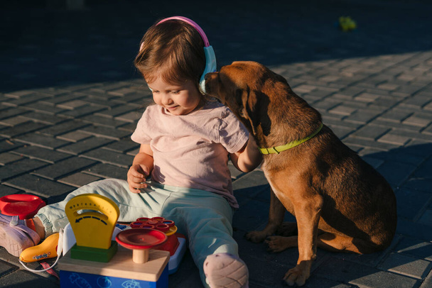 Malá kavkazská holčička si hraje s hračkami na dvorku, na hřišti. Vtipná holčička na letních prázdninách. Vodní park. Dovolená. - Fotografie, Obrázek