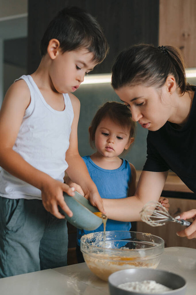 Щаслива сім'я на кухні готує тісто, випікає печиво. Сім'я з дитиною проводить час на домашній кухні вранці
. - Фото, зображення