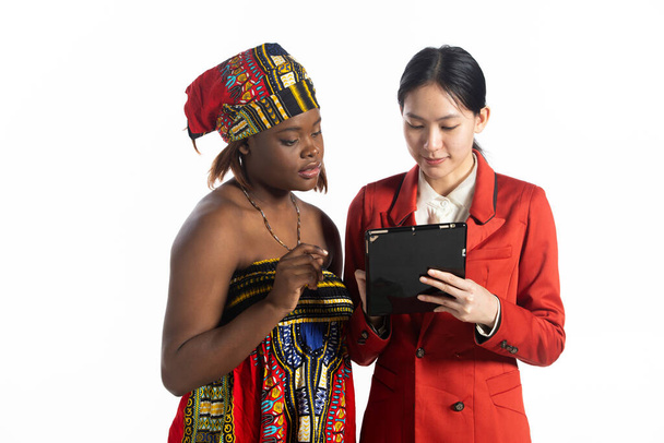 多民族の若い女性が一緒にタブレットを見て、ビジネス女性の笑顔積極的な表現。人種間のアフリカの女性、アジアの女性、 2人、人種統一ビジネスの多様性の概念。隔離。 - 写真・画像