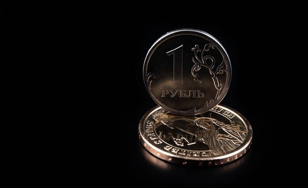 1Rus rublesi ve siyah bir arkaplanda 1 Amerikan doları değerinde bozuk paralar. - Fotoğraf, Görsel