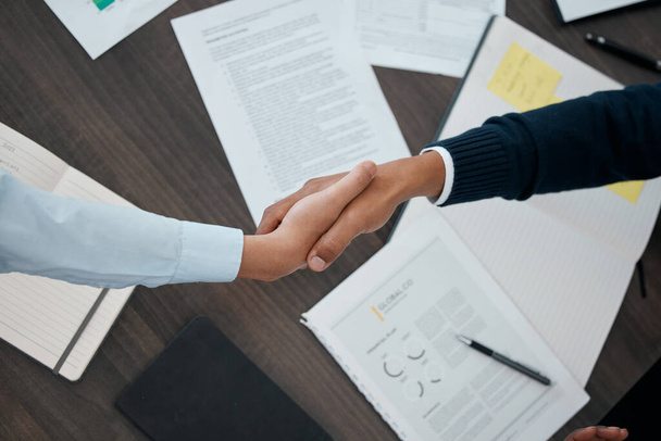 Business, hands and handshake with documents above paperwork for employment agreement or analysis at the office. Hand of people in partnership shaking for corporate contract, welcome or b2b meeting. - Foto, Imagem