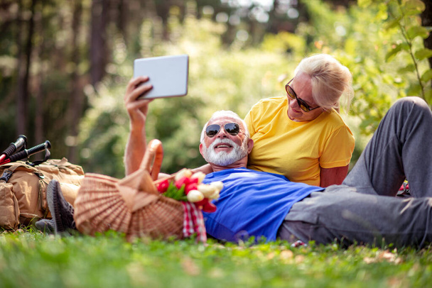 Senior couple enjoying in park,using tablet. Romantic moments. - Фото, зображення