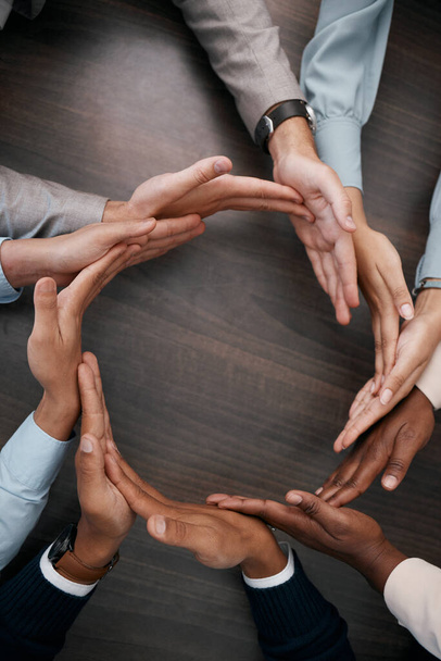 Hands, teamwork and synergy with business people in a circle or huddle as a team on a wooden table in the office. Collaboration, motivation and goal with an employee group working together on success. - Fotoğraf, Görsel