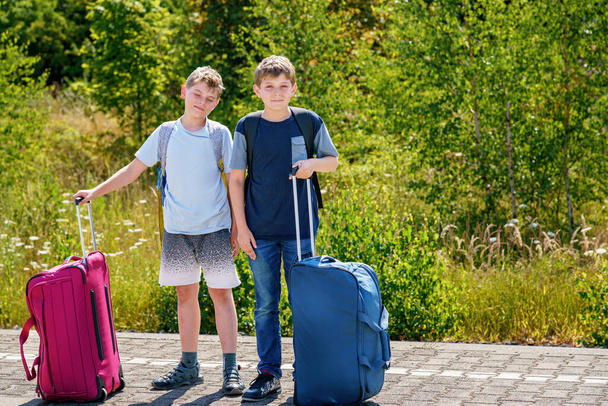 İki çocuk, yaz kampına gitmeden önce bavulları olan okul çocukları. Mutlu çocuklar, kardeşler, seyahate çıkan ikizler, tren bekleyen aile gezisi. - Fotoğraf, Görsel
