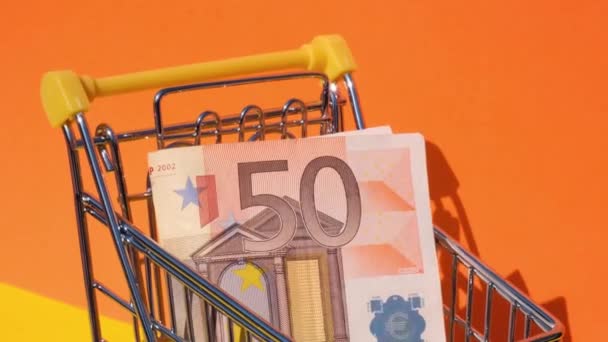50 euro banknot Pieniądze w wózku sklepowym zabawki wózek na żółtym tle. Koszyk z banknotami euro. Koncepcja minimalnego wynagrodzenia minimalnego: kredyt, inwestycja - Materiał filmowy, wideo