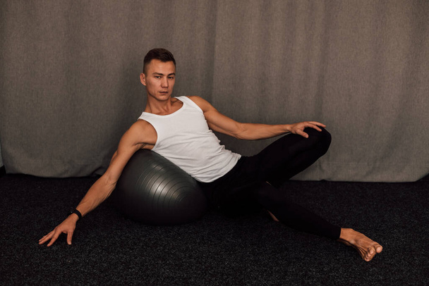 Un joven atleta realiza ejercicios en casa. Fitness Fitball Yoga Pilates. Foto de alta calidad - Foto, imagen