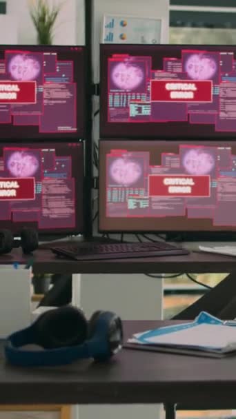 垂直ビデオ:コンピュータモニタを備えた空のオフィスでは、システムエラーとハッキング攻撃が代理店に表示され、セキュリティ違反警告が表示されます。重大なエラーメッセージが点滅し、ハッキングされたサーバーを持つ画面. - 映像、動画