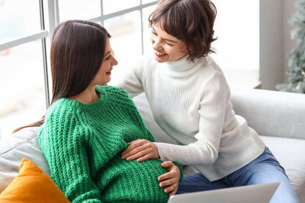 Young pregnant woman with her wife at home on Christmas eve - Foto, Imagem