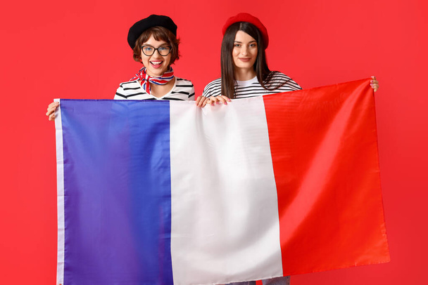 Kızıl arka planda Fransa bayrağı taşıyan genç kadınlar - Fotoğraf, Görsel
