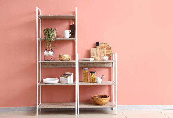 Scaffali con cibo, piante d'appartamento e utensili da cucina vicino alla parete rosa - Foto, immagini
