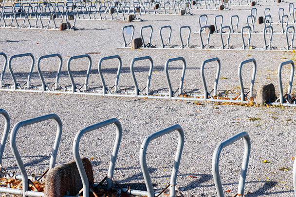 Suuri joukko moderneja pyörätelineitä sulkukunnossa suurella yleisellä pysäköintialueella. - Valokuva, kuva