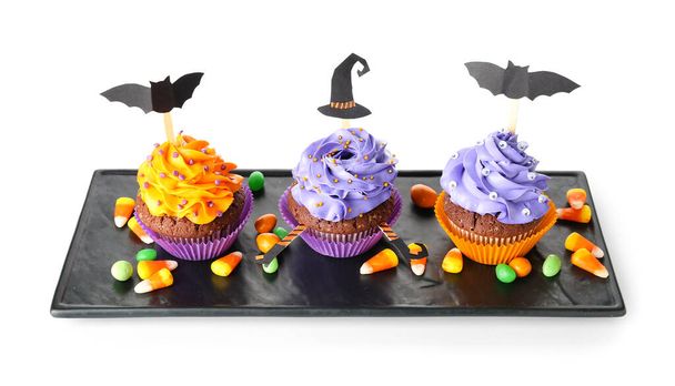 Board with tasty Halloween cupcakes and candies on white background - Photo, Image